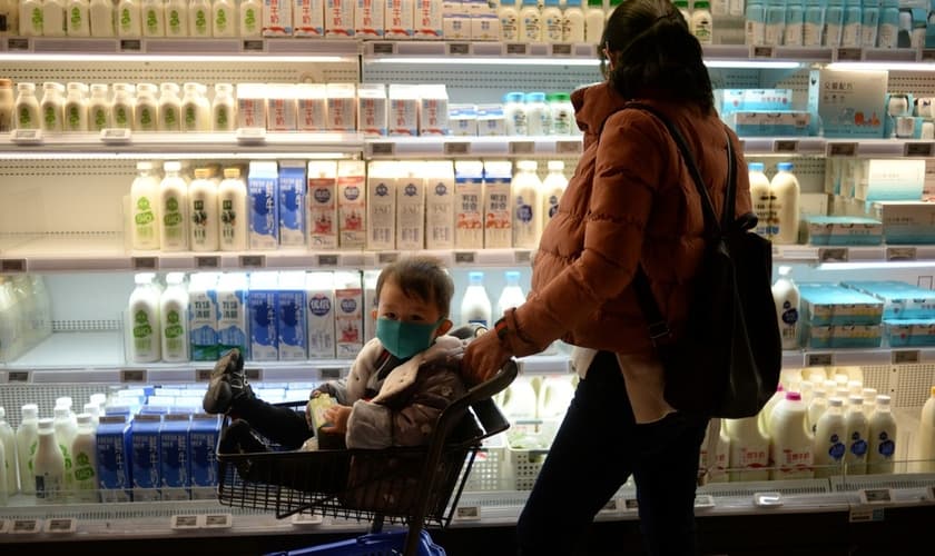 Mulher faz compras com bebê usando máscara em Pequim, em meio à epidemia de coronavírus na China. (Foto: Tingshu Wang/Reuters)