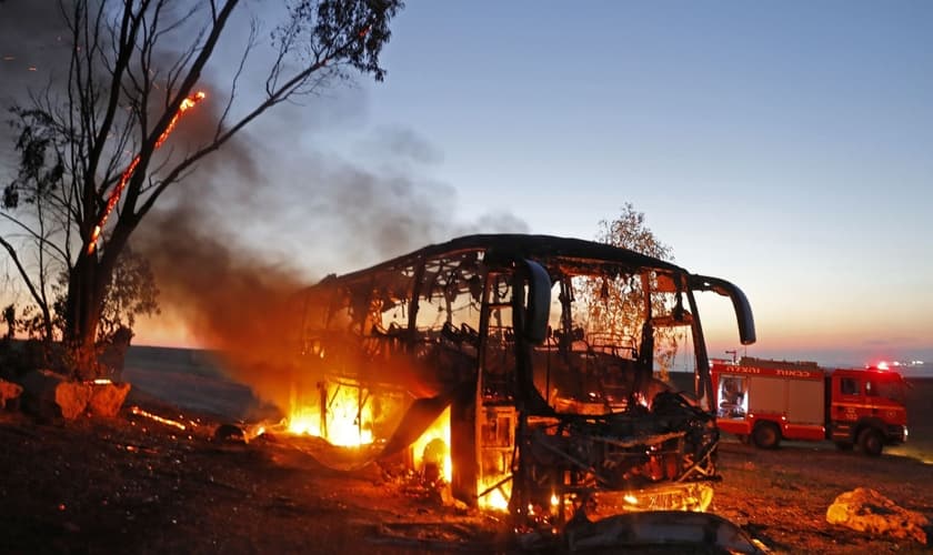 Ônibus em chamas depois de ser atingido por um foguete disparado da Faixa de Gaza, perto do kibutz de Kfar Aza. (Foto: Menahem Kahana/AFP)