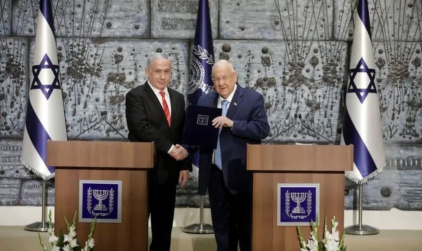 O presidente de Israel, Reuven Rivlin, dá as mãos ao primeiro-ministro Benjamin Netanyahu, como o escolhido para permanecer no cargo e formar governo no país. (Foto: Sebastian Scheiner/AP)