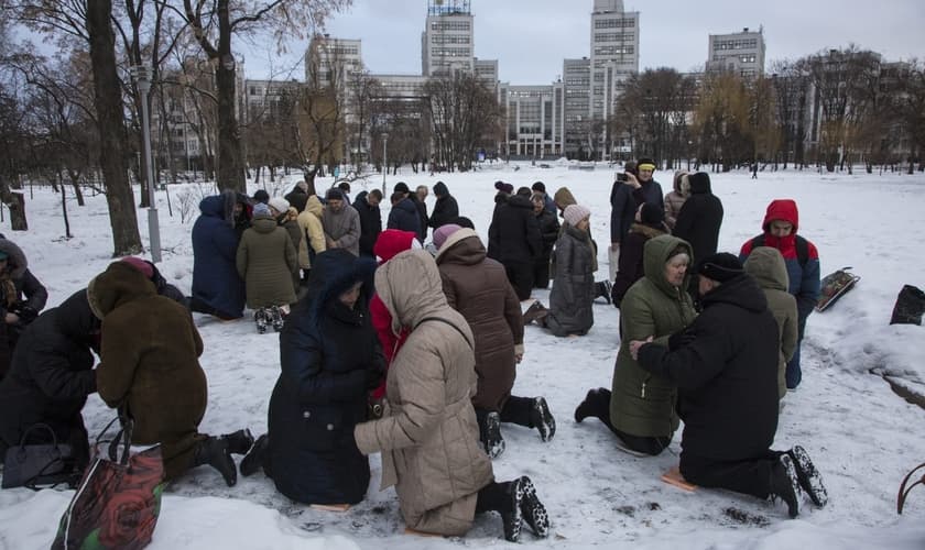 Ucranianos se ajoelham e oram na neve em praça da cidade de Kharkov (Foto: Reprodução/IMB)