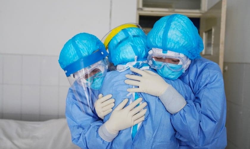 Membros da equipe médica se abraçando em uma ala de isolamento em um hospital em Zouping, no leste da China. (Foto: Stringer/AFP)